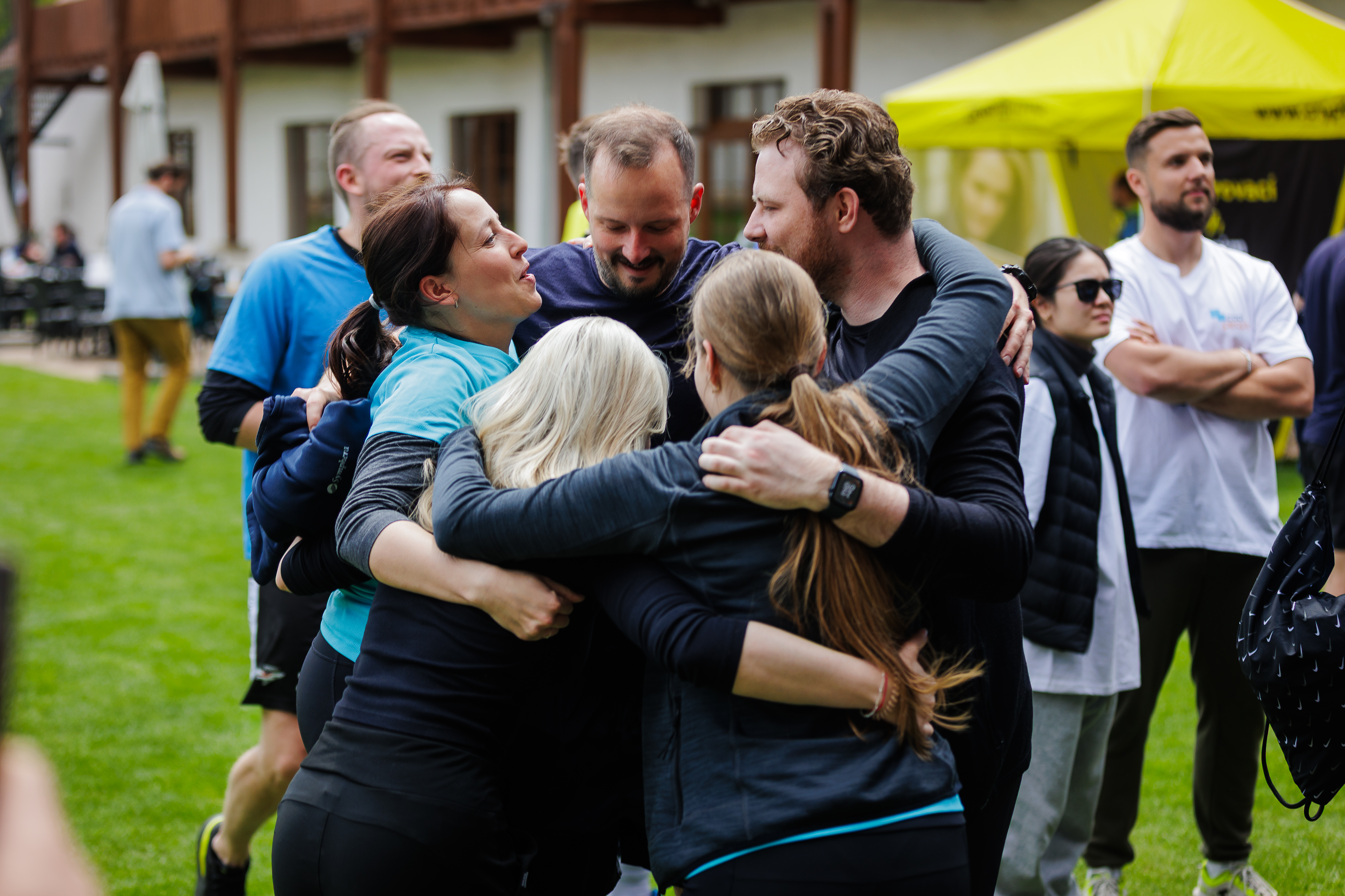 Účastníci v rozhovoru venku na akci Agile Race, jeden v mikině Agile Race